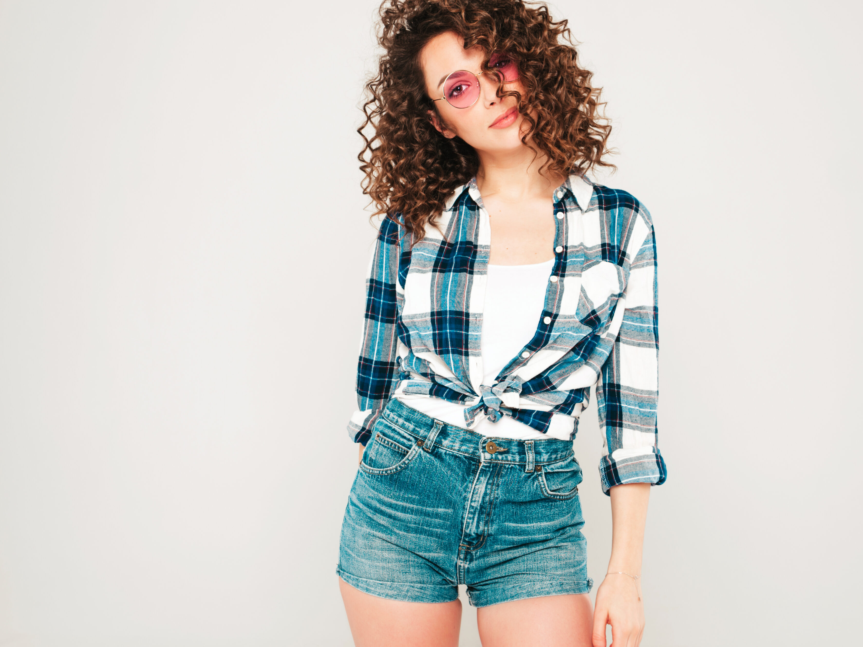 Portrait of beautiful smiling model with afro curls hairstyle dressed in summer hipster clothes.Sexy carefree girl posing in studio on gray background.Trendy funny and positive woman